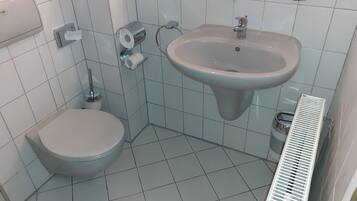 A bathroom with a toilet, sink, and hand dryer.