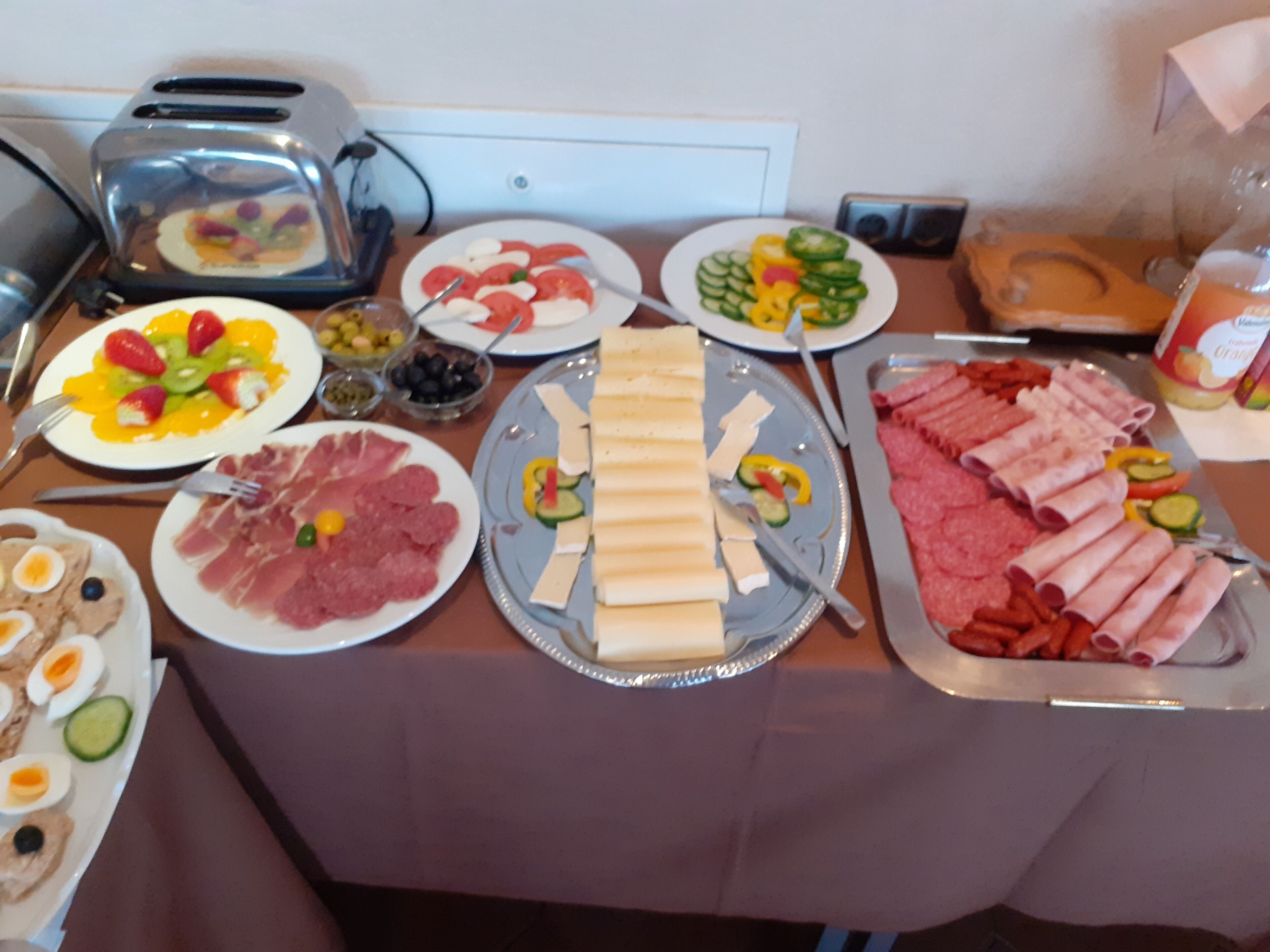 A buffet table with various food items including meats, cheeses, and vegetables.