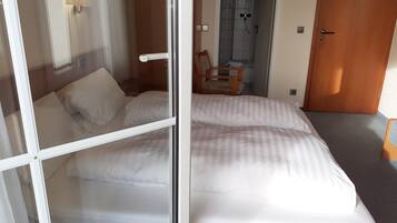 Une chambre d’hôtel avec un lit, une chaise, une douche et une porte.