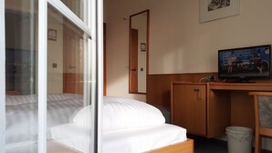 A hotel room with a bed, a television, a wooden desk, a trash bin, and a framed picture on the wall. - Edit Pension Rossau (Rossau)
