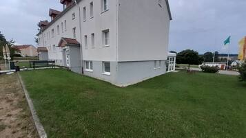 Ein mehrstöckiges Gebäude mit flachem Dach und einem kleinen Garten davor.