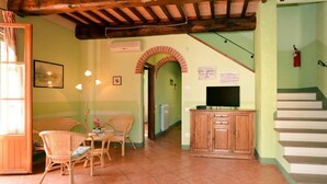 A cozy living area with a wooden ceiling, a dining table with chairs, a television, and a staircase. - VILLA CASALE IL BOSCHETTO - JACUZZI & FITNESS & PLAYGROUND OPEN AIR (Certaldo (Firenze))