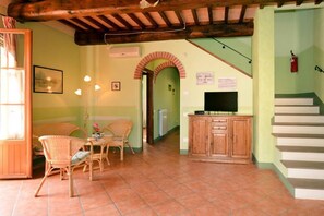 A cozy living area with a wooden ceiling, a dining table with chairs, a television, and a staircase. - VILLA CASALE IL BOSCHETTO - JACUZZI & FITNESS & PLAYGROUND OPEN AIR (Certaldo (Firenze))