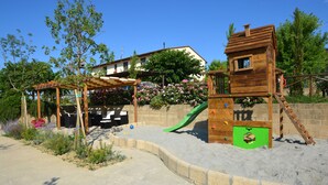 A children's play area with a wooden slide, a climbing structure, and a covered seating area. - VILLA CASALE IL BOSCHETTO - JACUZZI & FITNESS & PLAYGROUND OPEN AIR (Certaldo (Firenze))