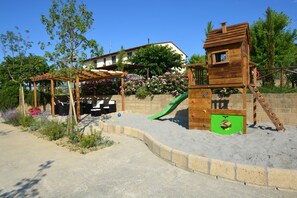 A children's play area with a wooden slide, a climbing structure, and a covered seating area. - VILLA CASALE IL BOSCHETTO - JACUZZI & FITNESS & PLAYGROUND OPEN AIR (Certaldo (Firenze))