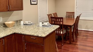 A kitchen with wooden cabinets, a granite countertop, and a dining area with a table and chairs. - Newly Remodeled! Near Old Town - 2 metros - Solar Home away from home 1600sq (Alexandria)