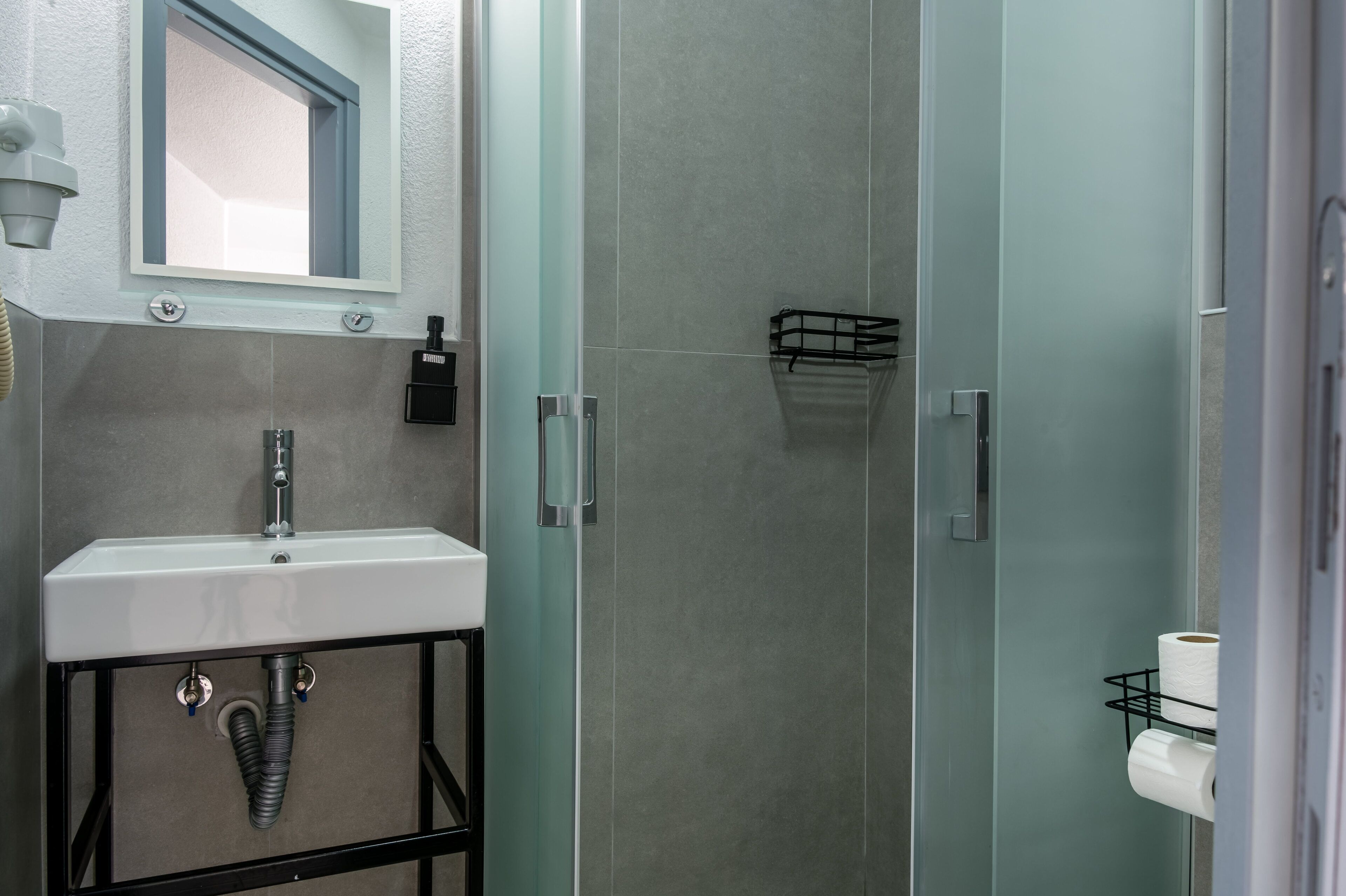 Une salle de bain moderne avec un lavabo, un miroir et un espace douche.