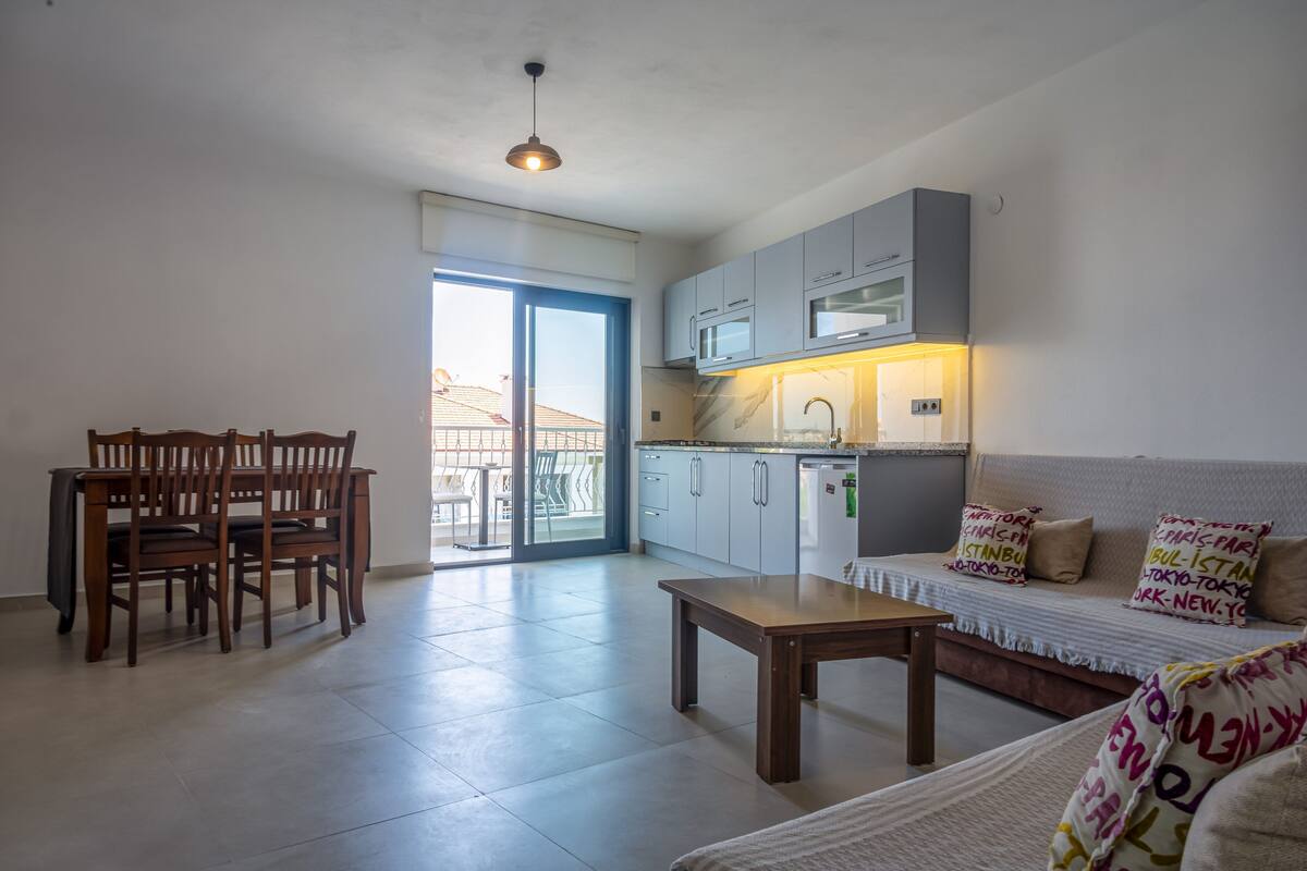 Eine moderne Wohnung mit Essbereich, einer Couch, einer Küche und einem Balkon.