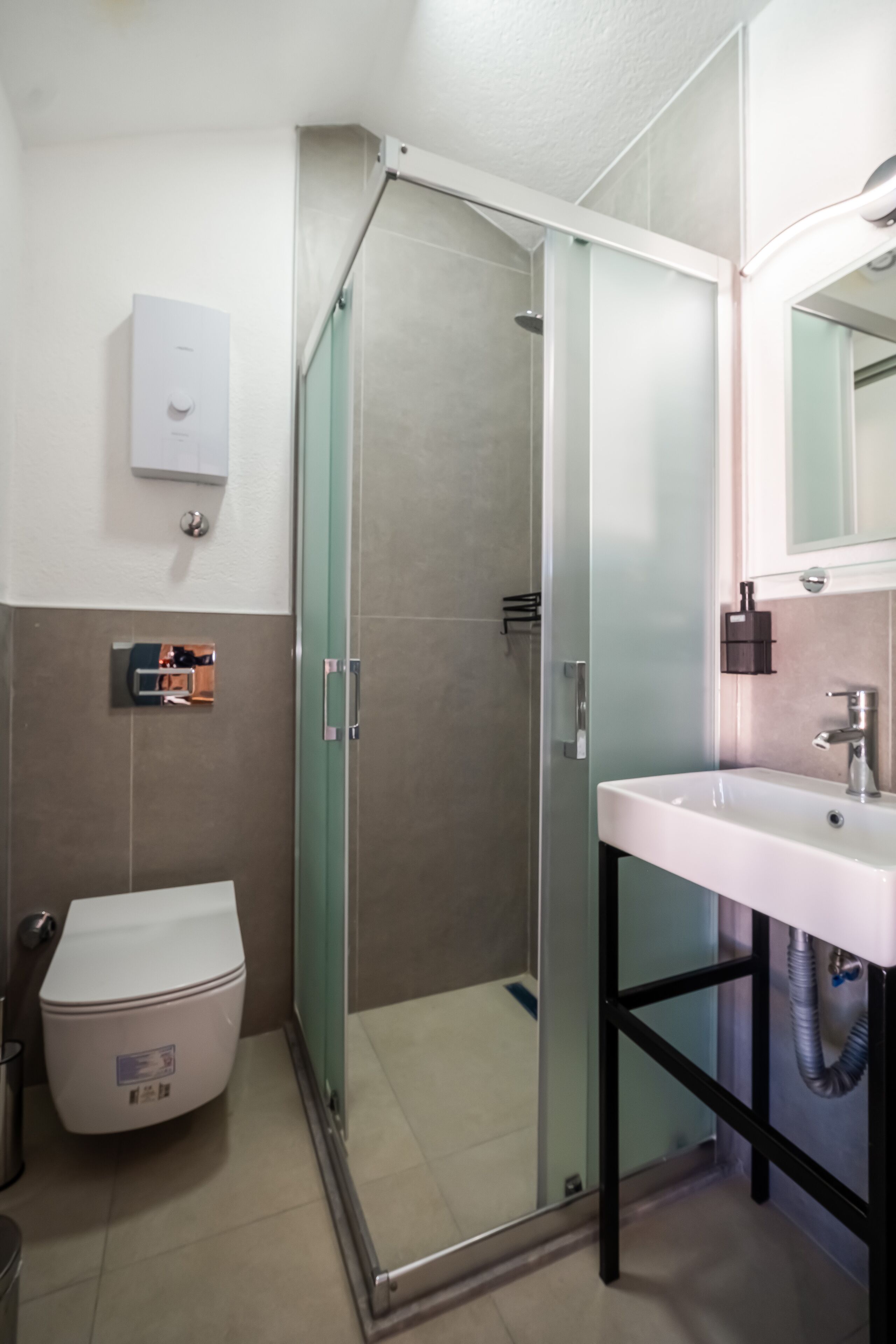 A bathroom with a glass-enclosed shower, a white sink, and a toilet.