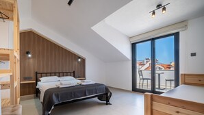 A modern bedroom with a bed, wooden furniture, a large window, and a view of buildings.