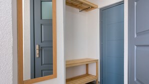 A hallway with a blue door, a wooden shelf, and a hanging drying rack.