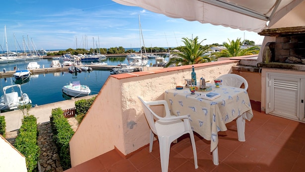 A terrace with a table and chairs overlooking a marina with boats. - Fantastic Sardinia casa capitano CAP01 (Budoni)