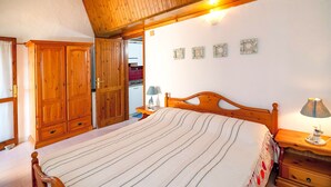 A bedroom with a large bed, wooden wardrobe, and bedside table with lamp. - Fantastic Sardinia casa capitano CAP01 (Budoni)