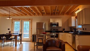 Eine geräumige Küche mit Holzbalken, einem Essbereich mit Tisch und Stühlen sowie einer gemütlichen Sitzecke mit Ledersofa.