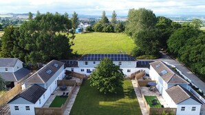 A residential complex with multiple houses, a central lawn, and solar panels on the roofs. - Beech Cottage - UK11845 (Carkeel, near Saltash)
