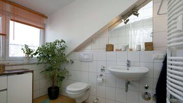 Ein Badezimmer mit Waschbecken, Toilette und einer Topfpflanze.