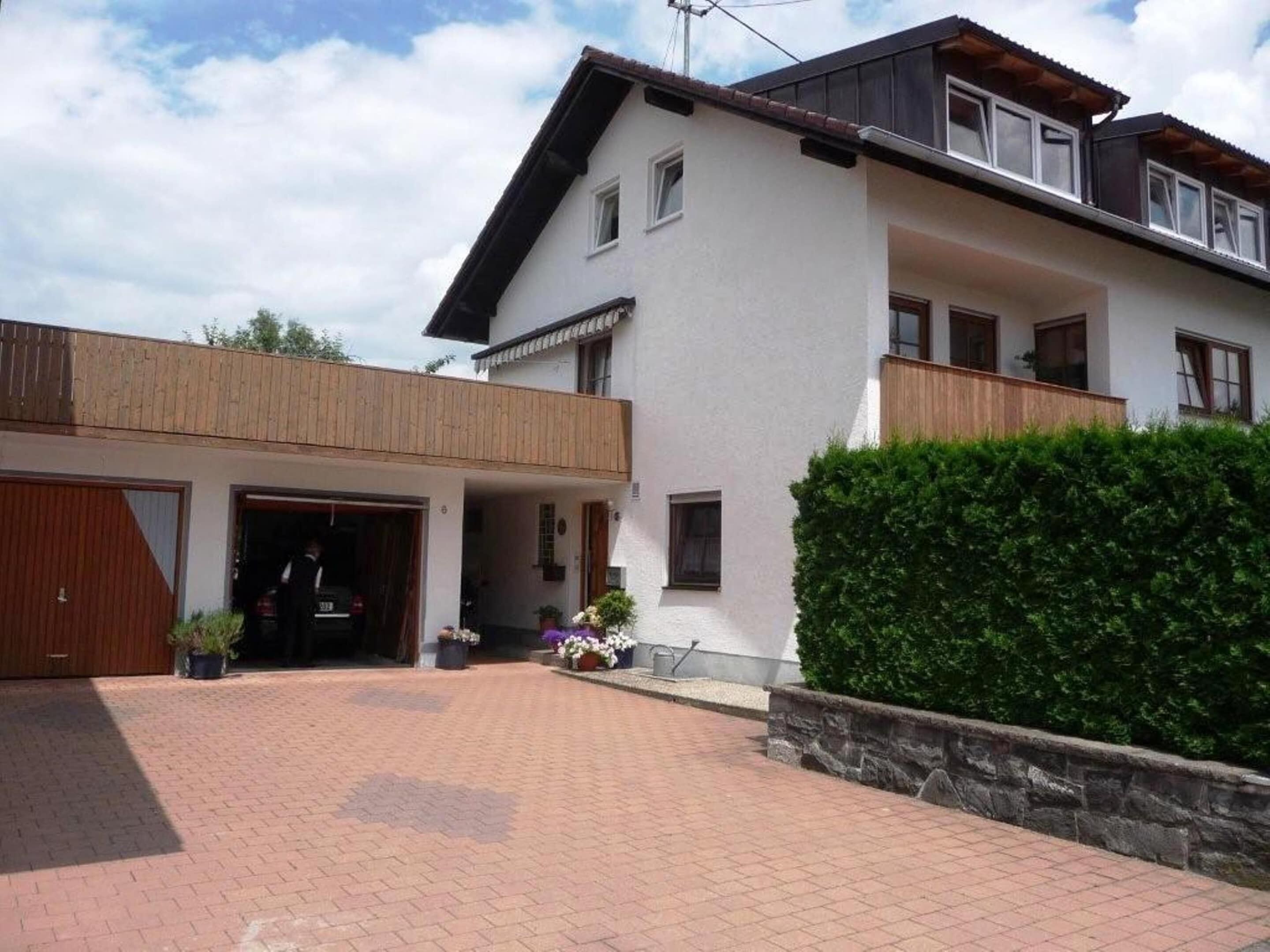 Ein modernes, zweistöckiges Haus mit Garage, überdachter Veranda und gepflegtem Heckenstreifen.