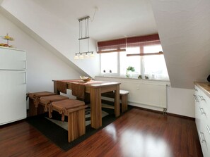 Enjoy meals in this kitchen with a dining table and bench, a refrigerator, and a window offering a view of the outdoors.