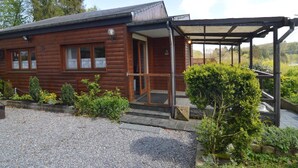 Une cabane en bois dotée d’un porche couvert et d’une allée en gravier.