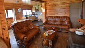 L’intérieur chaleureux d’un chalet comprend un salon avec deux canapés en cuir, une table basse en bois et un coin repas avec une table et des chaises.