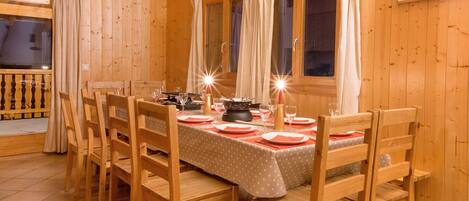 A wooden dining room with a table set for four, chairs, and curtains.