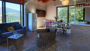 A spacious living area with a sofa, wicker chairs, a dining table, and a kitchen area with a refrigerator. - Holiday Home With Pool Near Assisi (Assisi)