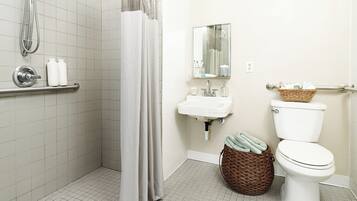 A bathroom with a shower, toilet, sink, and a mirror.