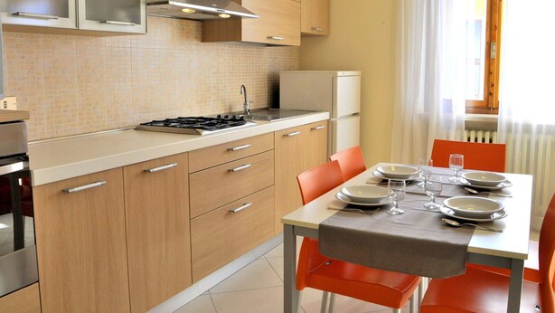 A compact kitchen with a gas stove, a refrigerator, and wooden cabinets. - Holiday Home in Lazise Near Lake Garda (Lazise)