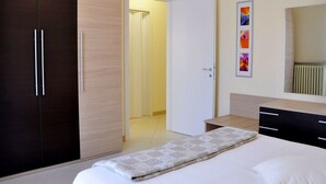A bedroom with a bed, a wardrobe, a bedside table, and a mirror. - Holiday Home in Lazise Near Lake Garda (Lazise)