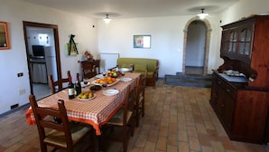 Un coin repas avec une nappe à carreaux, des chaises en bois et une table de buffet garnie de fruits et de boissons.