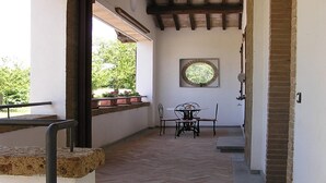 Un couloir avec un plafond en bois, une fenêtre offrant une vue circulaire, une table avec des chaises et un mur en briques.