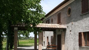 Un espace extérieur abrité comprenant un banc, une pergola et un bâtiment doté d’un toit en tuiles et de murs en briques.