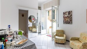 A spacious living area with a checkered table, two patterned armchairs, a dining table with cutlery and glasses, a radiator, and a door with a 'no entry' sign. - Cozy Mansion near Lake in Baveno Italy (Baveno)