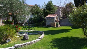 Un jardín con un muro de piedra, un pequeño edificio de piedra y una bicicleta.