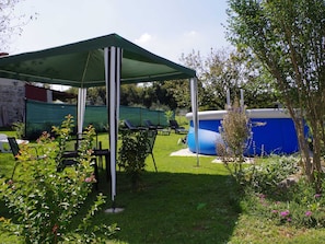 A covered outdoor seating area with chairs and a table, a swimming pool, and a garden with various plants. - Holiday Home in Sajini With Pool Near Beach (Barban)