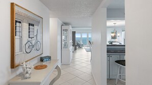 A modern kitchen with white cabinets, a black countertop, and a dining area with a white table and chairs. - GULF FRONT INDIAN ROCKS BEACH, REFLECTIONS VACATION CONDO (Indian Rocks Beach)
