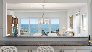 A kitchen with a view of the ocean, a chandelier, and a dining area with chairs and a table. - GULF FRONT INDIAN ROCKS BEACH, REFLECTIONS VACATION CONDO (Indian Rocks Beach)