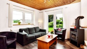 Een gezellige woonkamer met een houten plafond, een bank, een salontafel en een open haard.