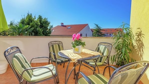 A patio with four chairs and a table, surrounded by a yellow wall and a red-tiled roof building in the background. - Modern Ground Floor Apartment With Private Terrace and Jacuzzi (Crikvenica)