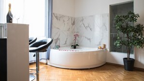 A modern bathroom with a marble wall, a bathtub, a potted plant, and a chair. - Trastevere Suite (Rome)