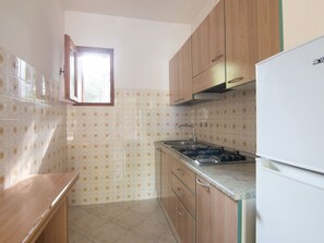 A kitchen with wooden cabinets, a gas stove, a sink, and a window.