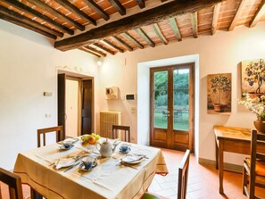 Un coin repas avec une table dressée pour quatre personnes, un radiateur et une porte donnant sur l’extérieur.