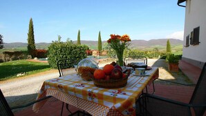 An outdoor dining area with a table set for two, surrounded by chairs. - Peaceful Pienza Garden Escape (Pienza)
