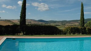 A swimming pool with a view of rolling hills and tall trees in the background. - Peaceful Pienza Garden Escape (Pienza)