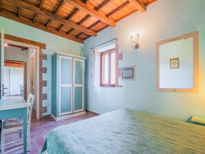 A room with a wooden ceiling, a bed, a table with chairs, a wardrobe, a window with curtains, and wall-mounted lights. - Holiday Home in Sellano With Pool & Sun Terrace (Sellano)