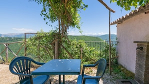 Een tafel met stoelen onder een boom, met uitzicht op bergen.