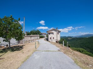A rural road leading to a small house with a stone wall and a metal gate. - Holiday Home in Sellano With Pool & Sun Terrace (Sellano)