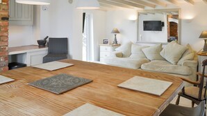 A cozy room with a wooden dining table, a white sofa, and a brick wall. - 5 bedroom accommodation in Tilney St Lawrence, near Kings Lynn (Tilney St Lawrence, near Kings Lynn)