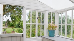 A conservatory with white paneled walls and a view of a garden. - 5 bedroom accommodation in Tilney St Lawrence, near Kings Lynn (Tilney St Lawrence, near Kings Lynn)