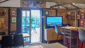 A cozy bar area with a television, wooden beams, and a view of the outdoors. - 5 bedroom accommodation in Tilney St Lawrence, near Kings Lynn (Tilney St Lawrence, near Kings Lynn)